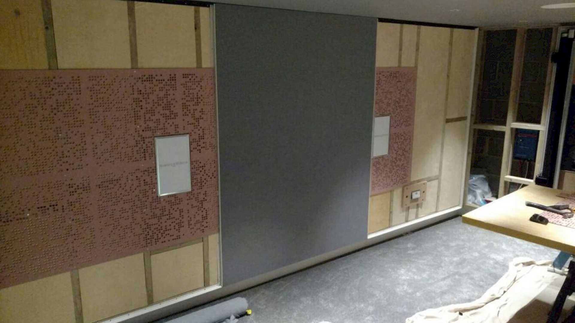 Image shows the home cinema side wall and acoustic treatment, with stretched fabric being installed.
