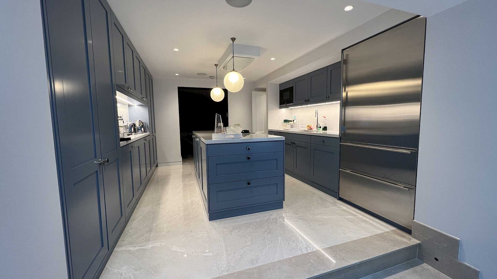 Image shows kitchen area with island. System includes Crestron Control, Lutron and Sonos.