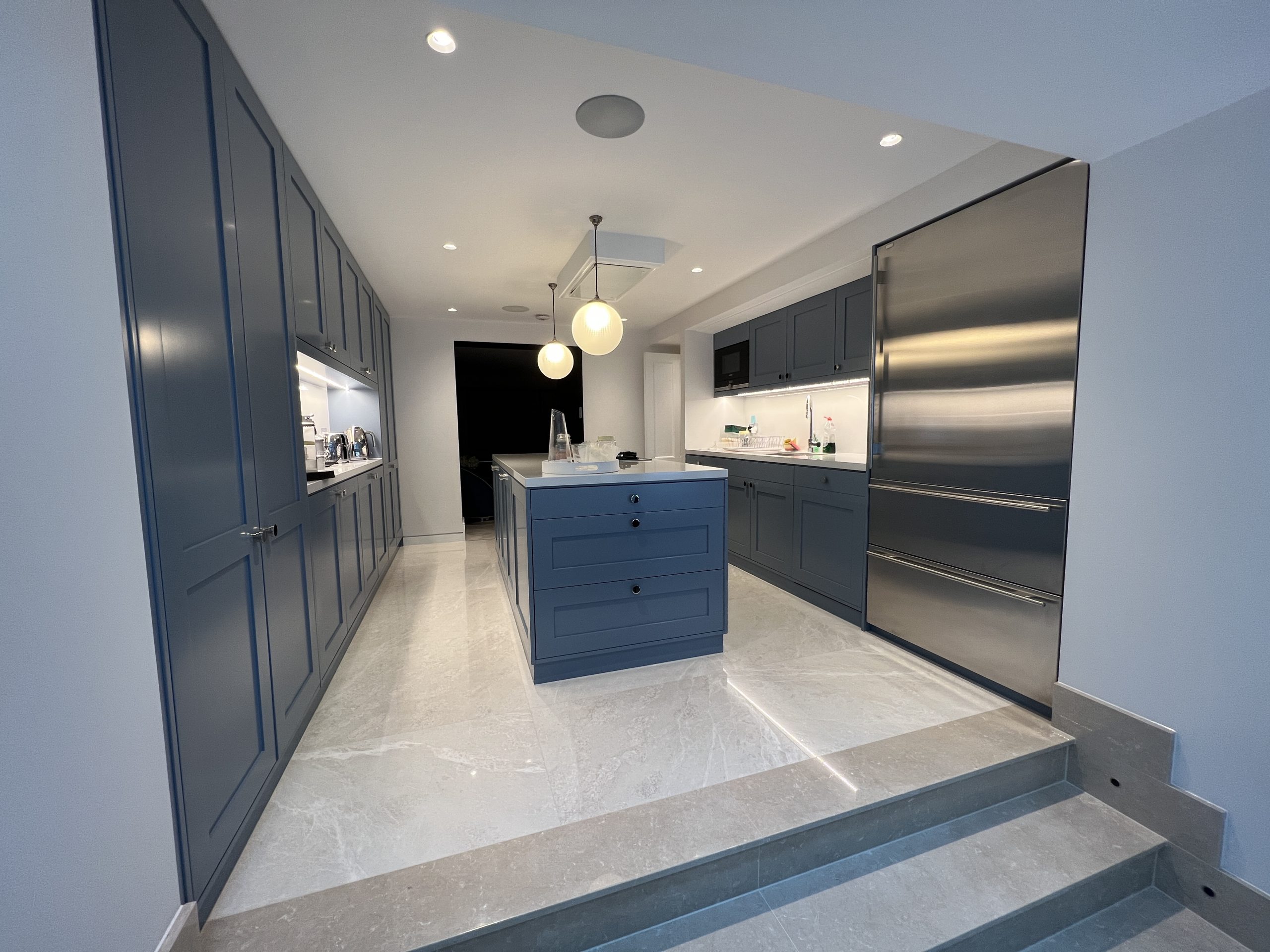 Image shows kitchen area with island. System includes Crestron Control, Lutron and Sonos.