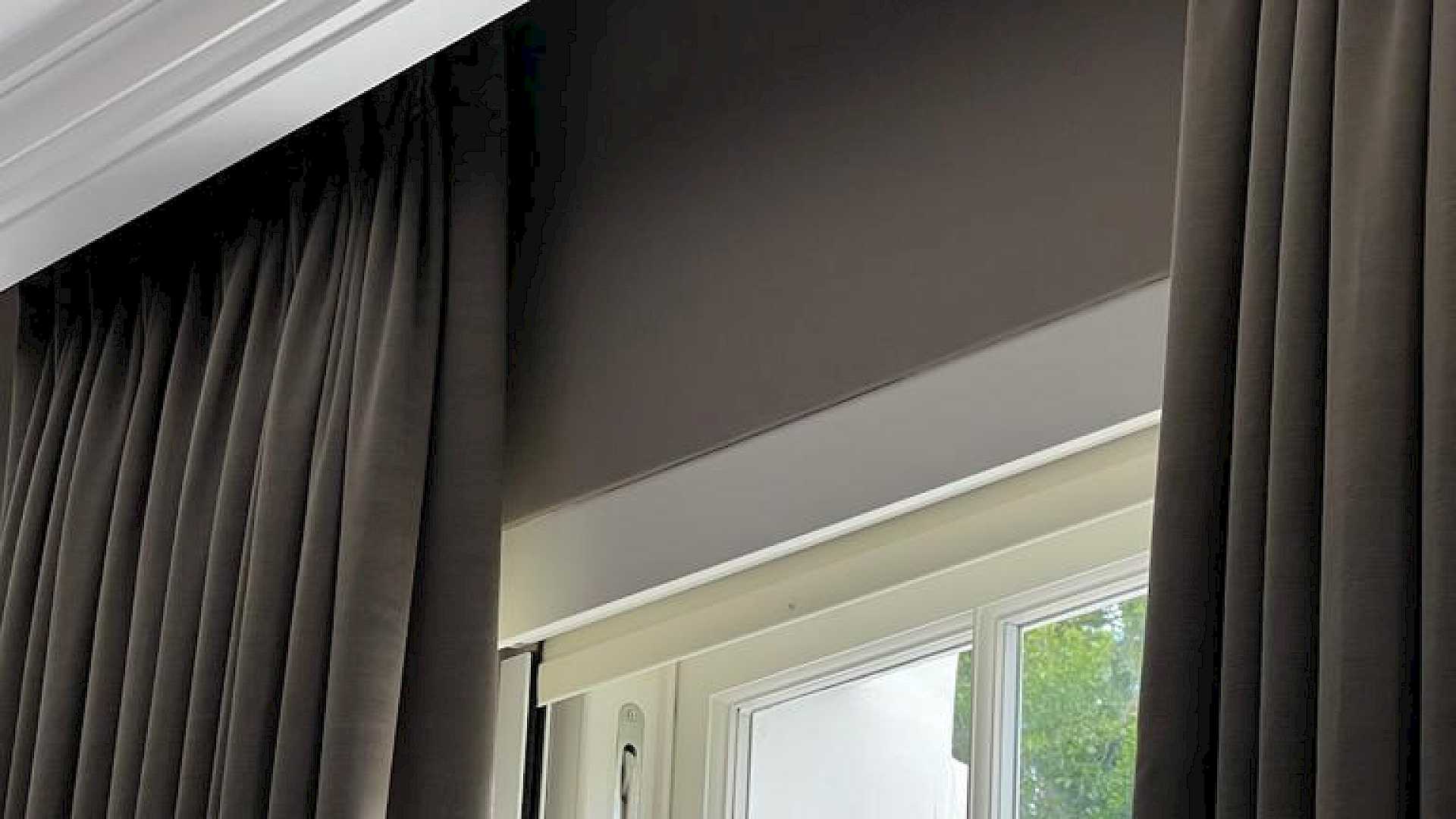 A closer view of a Lutron motorised blinds, set in the window with curtains showing.