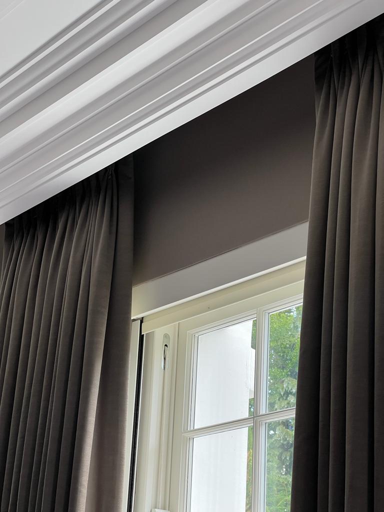 A closer view of a Lutron motorised blinds, set in the window with curtains showing.
