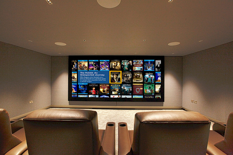 Home cinema room with immersive audio, Trinnov processing and Bowers and Wilkins in wall loudpseakers. Looking at screen from seating position. This image features in our how much does a home cinema cost article.